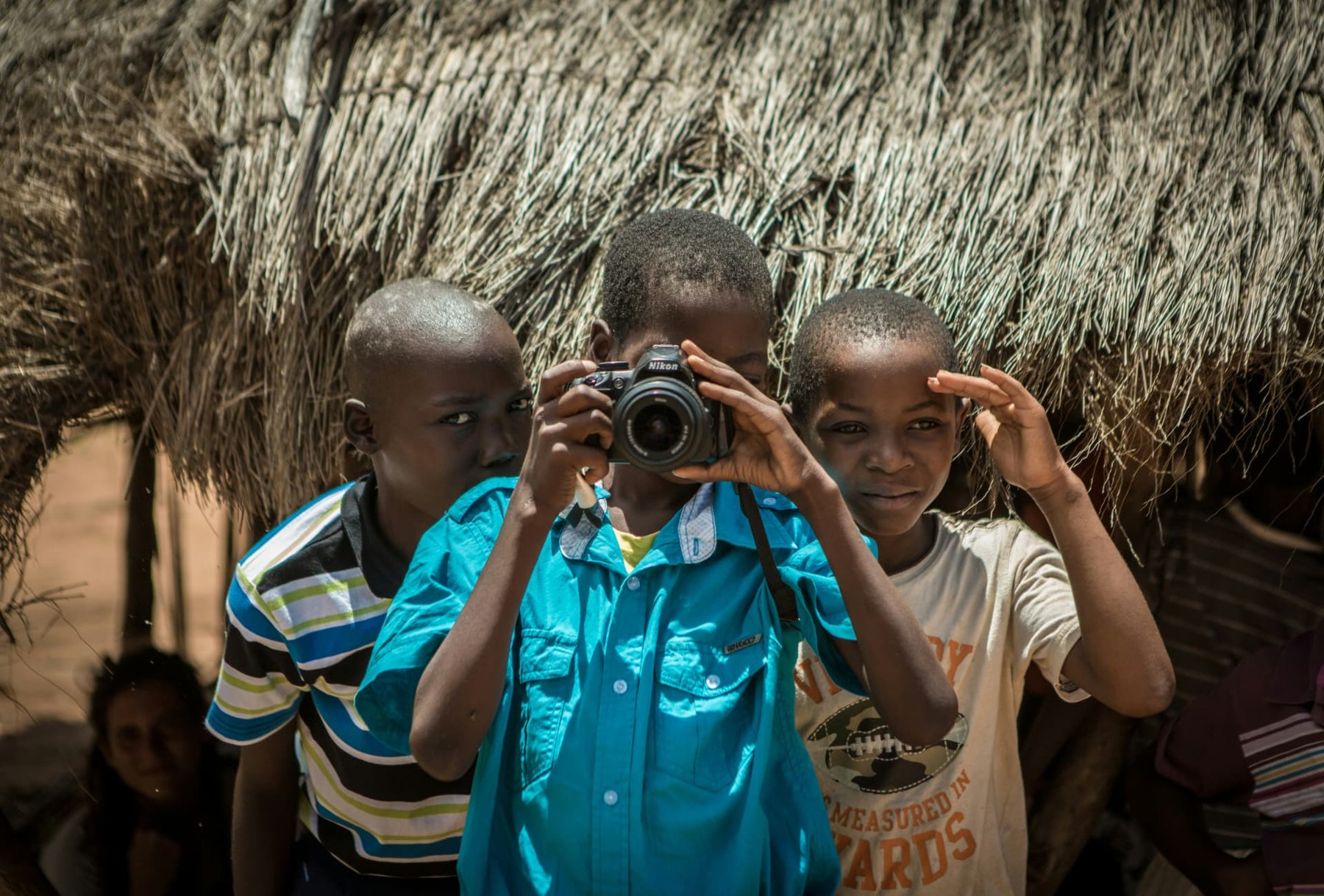 Three children exploring photography together in an African community